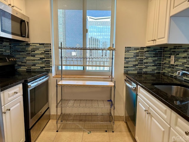 kitchen featuring backsplash, dark stone counters, light tile patterned flooring, white cabinetry, and stainless steel appliances