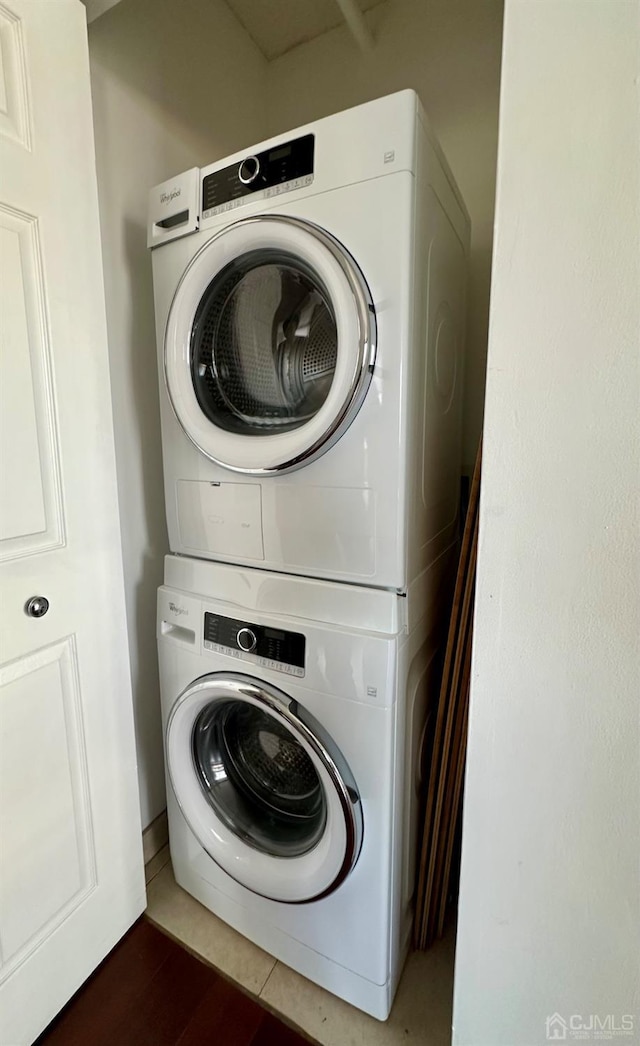 washroom with stacked washer and dryer and dark tile patterned flooring