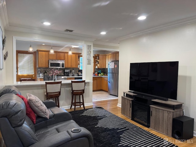 living room with visible vents, baseboards, ornamental molding, light wood-type flooring, and recessed lighting