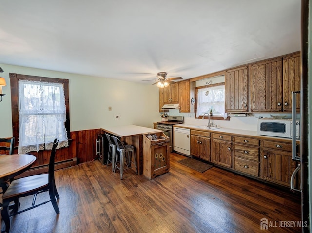 36 Frederick St, Carteret, NJ 07008 - kitchen featuring white appliances, under cabinet range hood, a peninsula, brown cabinets, and dark wood-type flooring