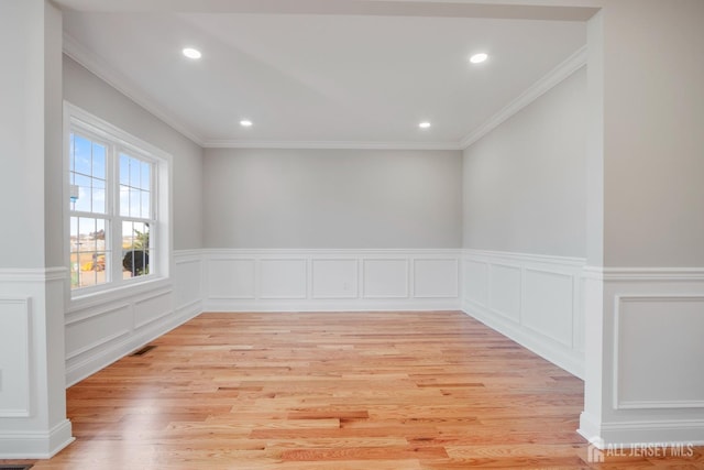 spare room featuring wainscoting, ornamental molding, light wood-style flooring, and recessed lighting