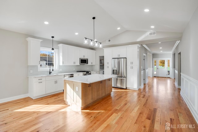kitchen featuring white cabinetry, a center island, visible vents, and appliances with stainless steel finishes
