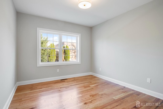 unfurnished room featuring light wood-style floors, visible vents, and baseboards