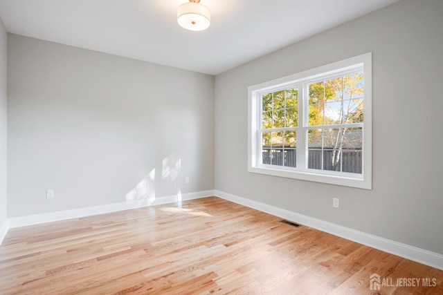 spare room featuring light wood-style floors, visible vents, and baseboards