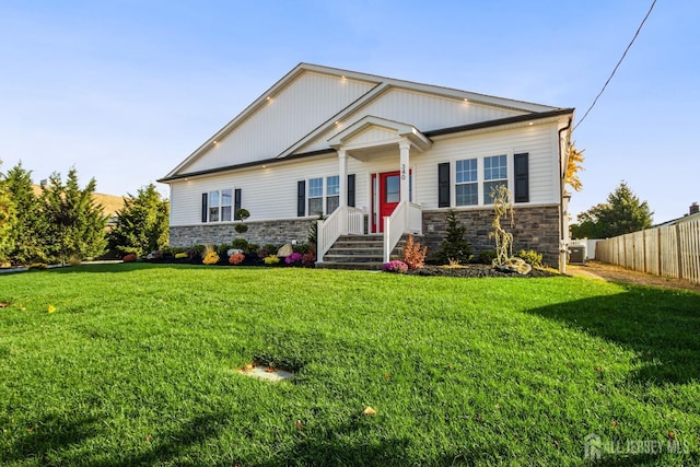 view of front of property featuring central AC, stone siding, a front yard, and fence