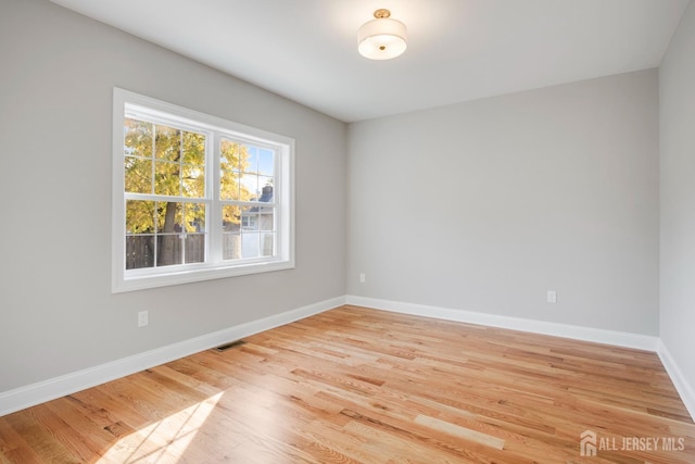 unfurnished room with baseboards, light wood-type flooring, and visible vents
