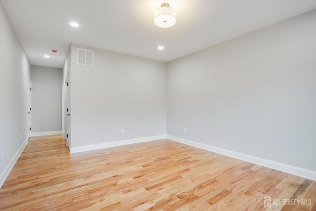 empty room featuring light wood-style floors, visible vents, baseboards, and recessed lighting