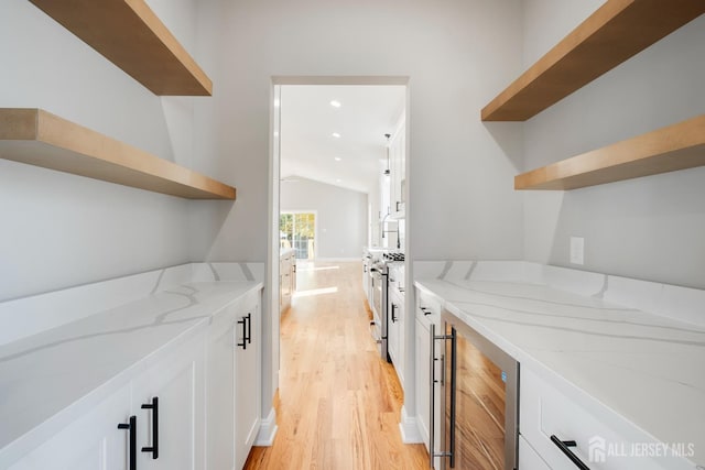 bar with lofted ceiling, gas range, light wood-style floors, and beverage cooler