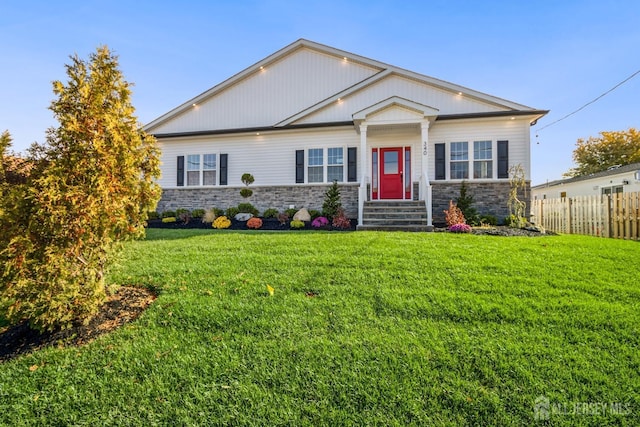 craftsman house featuring stone siding, fence, and a front lawn