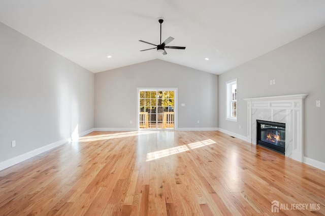 unfurnished living room featuring vaulted ceiling, ceiling fan, a fireplace, and light wood-style floors