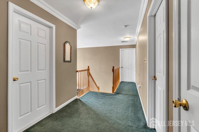 hallway featuring dark colored carpet, baseboards, ornamental molding, and an upstairs landing
