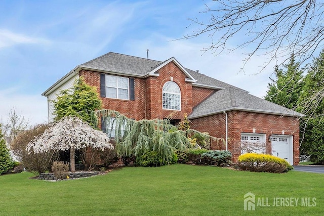view of front of house with a shingled roof, brick siding, and a front yard