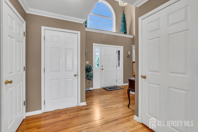 foyer with crown molding, a healthy amount of sunlight, light wood finished floors, and baseboards