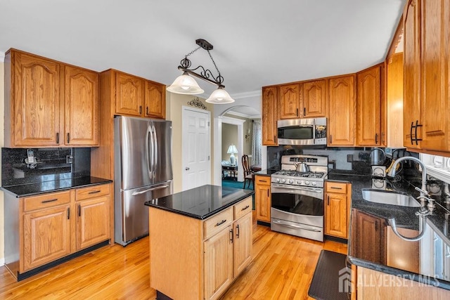kitchen featuring arched walkways, appliances with stainless steel finishes, a sink, and light wood finished floors