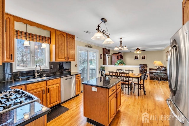 kitchen with stainless steel appliances, a center island, light wood-style flooring, a sink, and visible vents
