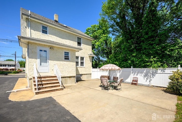 1909 Hamilton Blvd, South Plainfield, NJ 07080 - back of property featuring entry steps, stucco siding, a patio area, and outdoor dining area