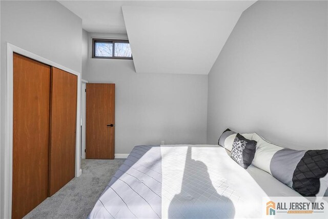 bedroom with a closet, light colored carpet, and lofted ceiling