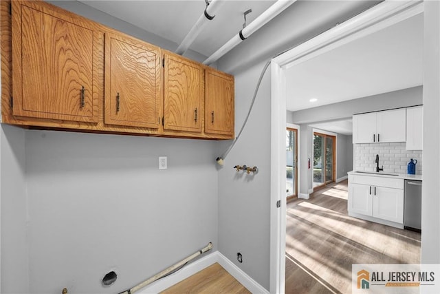 laundry room with washer hookup, cabinets, sink, and light hardwood / wood-style flooring