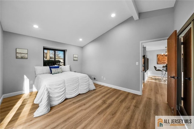 bedroom with lofted ceiling with beams and light hardwood / wood-style floors