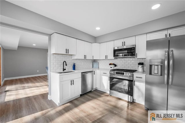 kitchen with hardwood / wood-style floors, sink, white cabinets, and stainless steel appliances