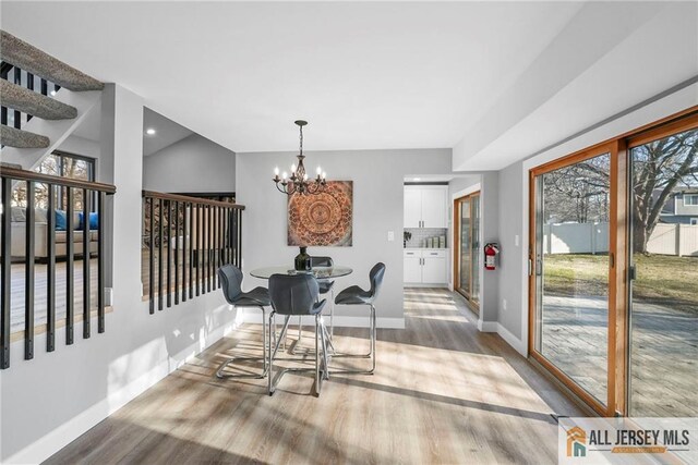 dining room featuring a chandelier, light hardwood / wood-style flooring, and vaulted ceiling