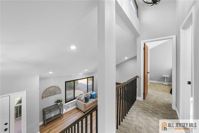 corridor featuring light colored carpet and lofted ceiling