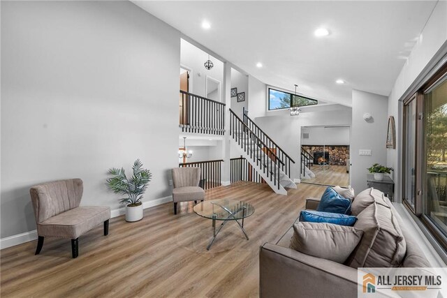 living room with wood-type flooring, high vaulted ceiling, and a notable chandelier