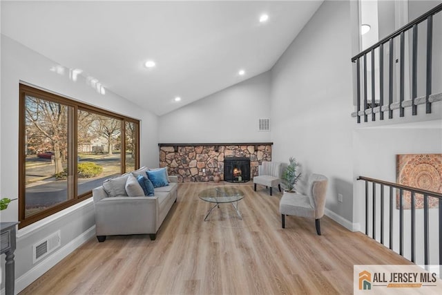 living room with light wood-type flooring, a wood stove, and lofted ceiling