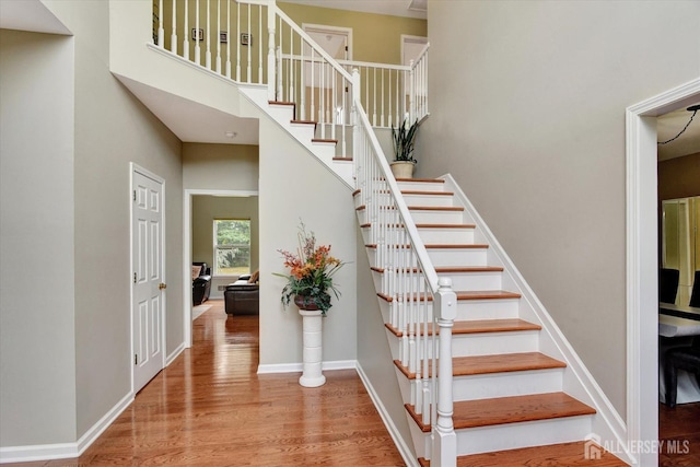 stairway featuring hardwood / wood-style flooring and a towering ceiling