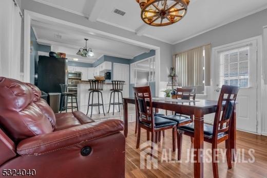 dining room featuring beam ceiling, light hardwood / wood-style floors, crown molding, and an inviting chandelier