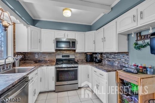 27 6th Ave, Port Reading, NJ 07064 - kitchen featuring appliances with stainless steel finishes, ornamental molding, light tile patterned floors, white cabinetry, and backsplash
