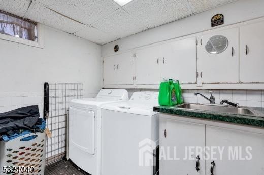 washroom with cabinets, washing machine and dryer, and sink