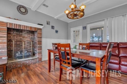 27 6th Ave, Port Reading, NJ 07064 - dining room with wood finished floors, beam ceiling, a chandelier, wainscoting, and a brick fireplace