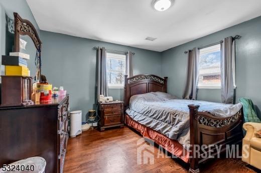 bedroom with multiple windows and dark wood-type flooring