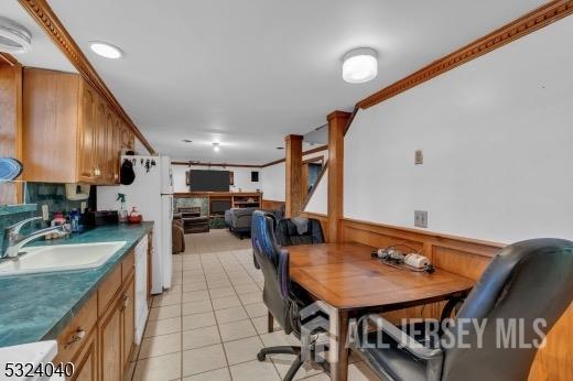 kitchen with sink, light tile patterned floors, white appliances, and ornamental molding