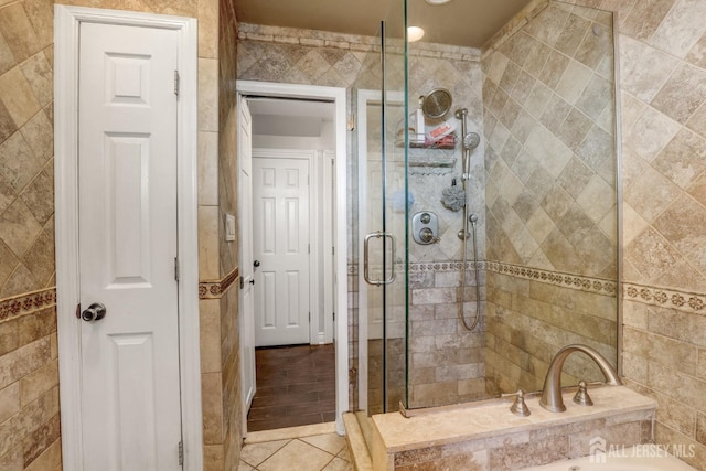 full bath featuring a tub, tile walls, a shower stall, and tile patterned flooring