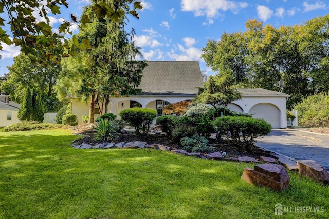 view of front of property with a garage, aphalt driveway, stucco siding, and a front yard