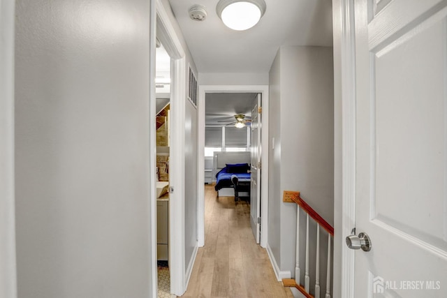 corridor with visible vents, light wood finished floors, and an upstairs landing