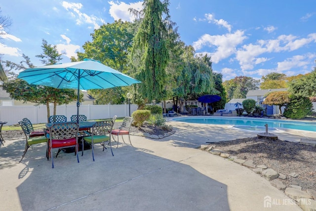 view of pool with a patio, fence, outdoor dining space, and a fenced in pool