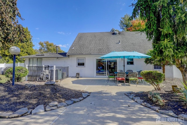 back of house with fence, a patio, stucco siding, and roof with shingles