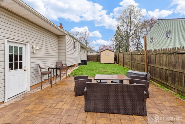 view of patio / terrace featuring a fenced backyard, an outbuilding, outdoor dining area, and a shed