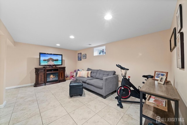 living room with light tile patterned floors, baseboards, a glass covered fireplace, and recessed lighting