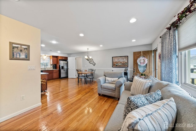 living room featuring baseboards, light wood finished floors, recessed lighting, and a chandelier