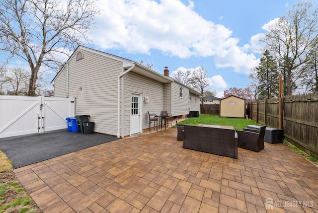 view of patio / terrace with an outdoor hangout area, a storage shed, a fenced backyard, a gate, and an outbuilding