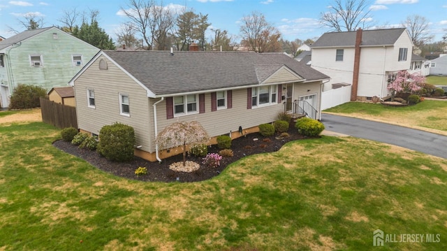 view of front of home with roof with shingles, a front yard, a gate, a garage, and fence