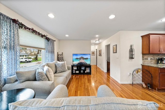 living room with recessed lighting, baseboards, bar, and light wood finished floors