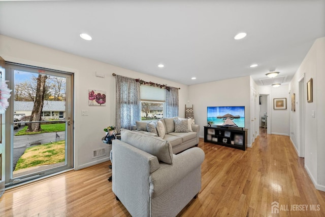 living room featuring visible vents, attic access, baseboards, and light wood-type flooring