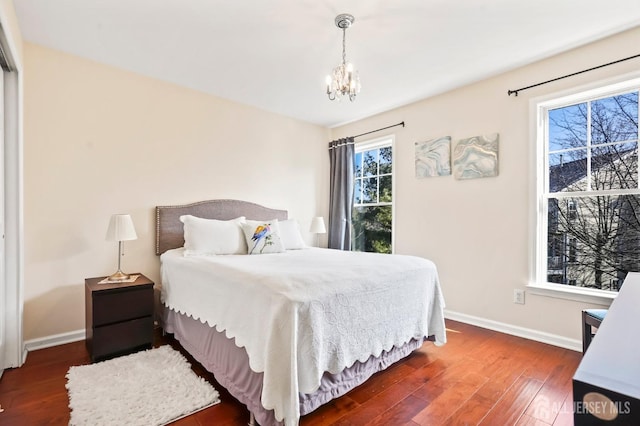 bedroom with dark hardwood / wood-style floors and an inviting chandelier