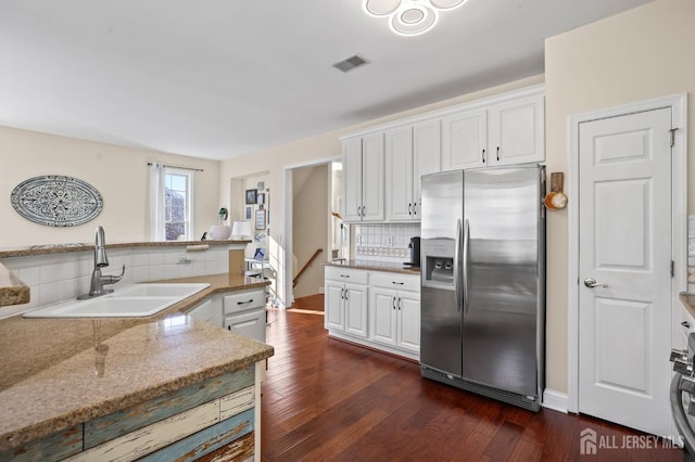 kitchen featuring white cabinetry, dark hardwood / wood-style flooring, stainless steel fridge, sink, and backsplash