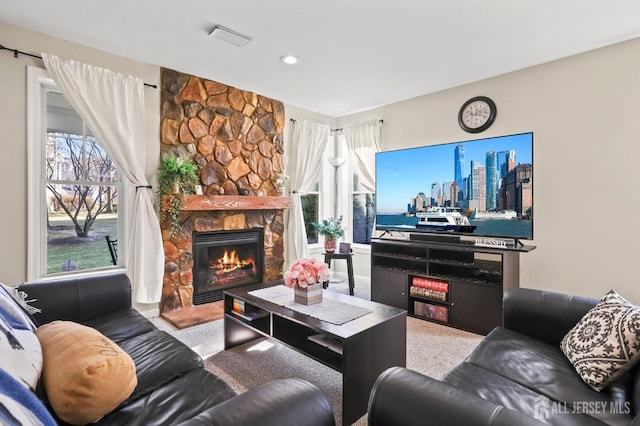 carpeted living room featuring a stone fireplace